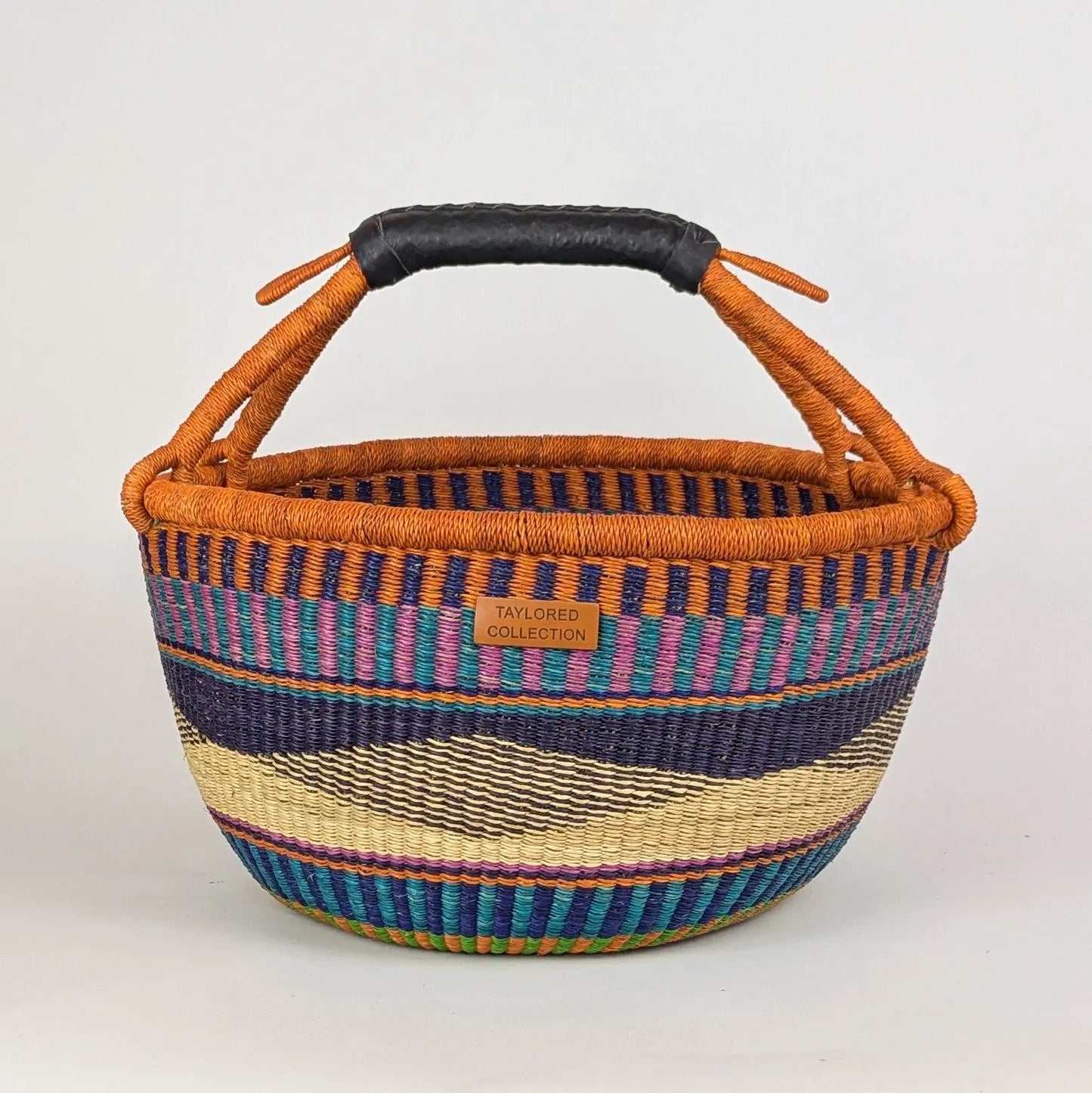 Woven basket with colorful stripes and a black handle on a white background
