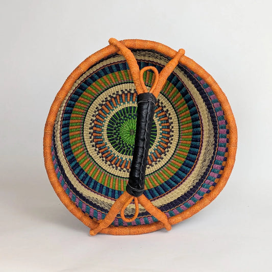 Woven basket with colorful pattern and orange handles on a light gray background