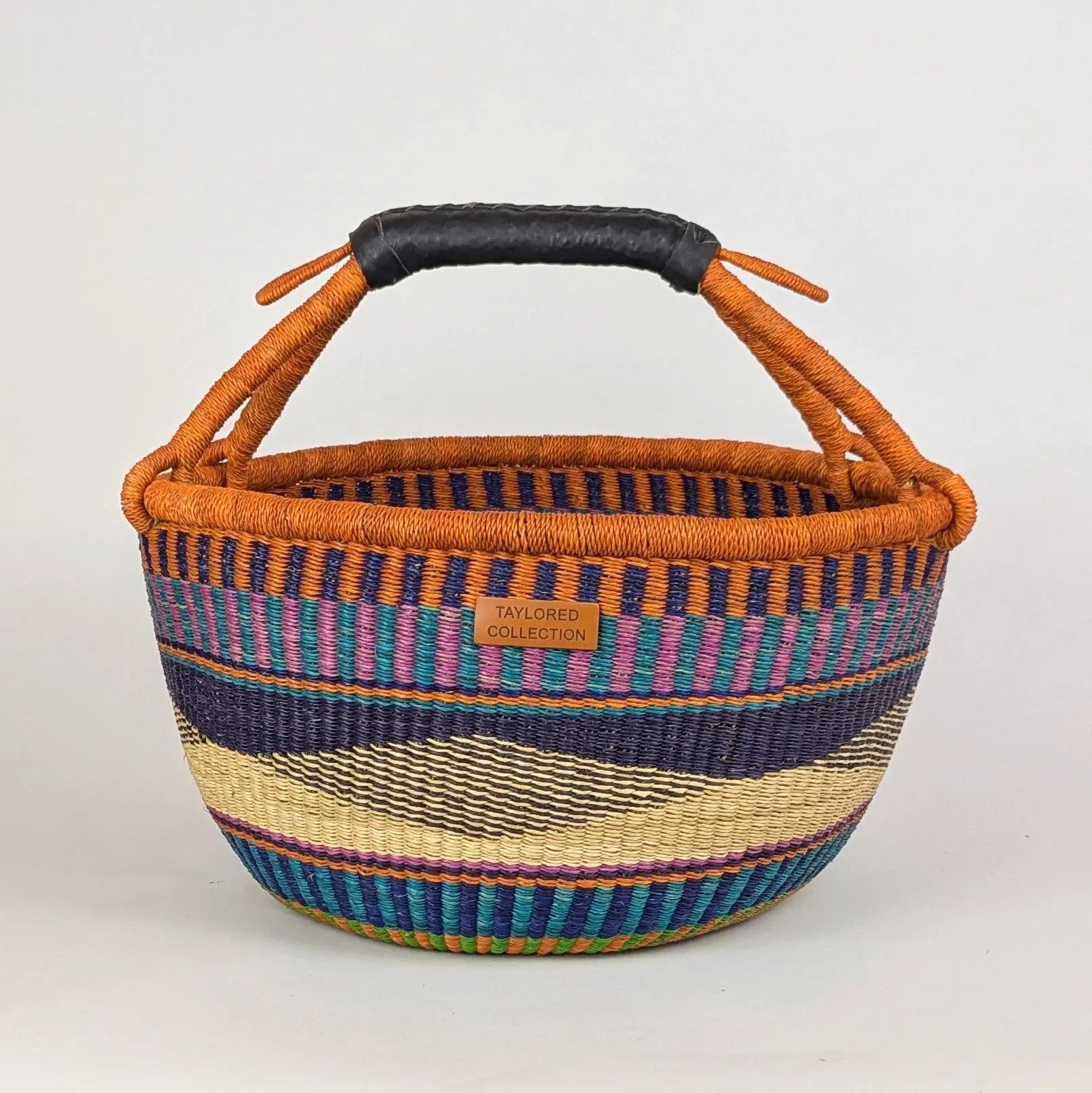 Woven basket with colorful stripes and a black handle on a white background