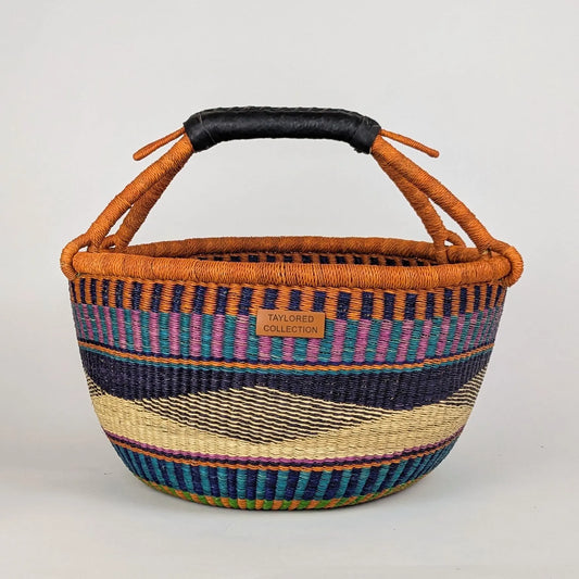 Woven basket with striped pattern and orange handle on a light gray background