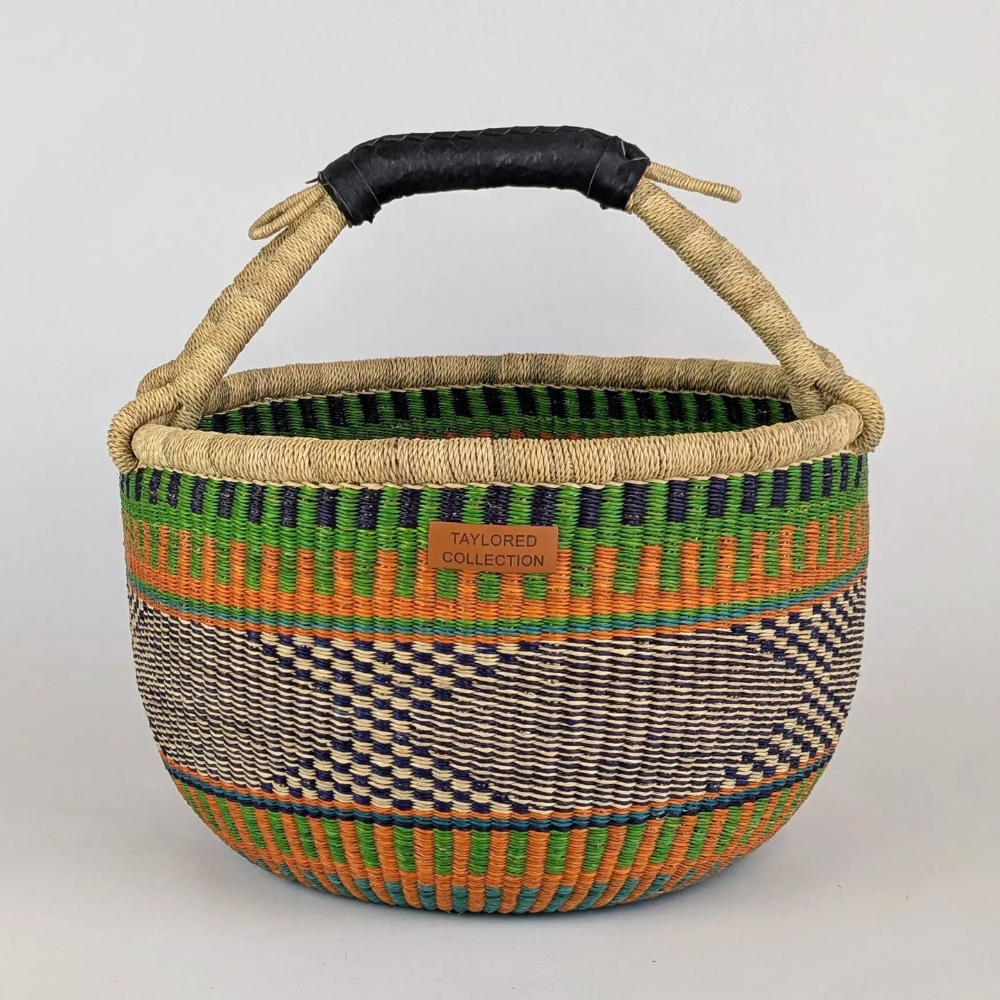 Woven basket with colorful patterns and a handle on a light gray background