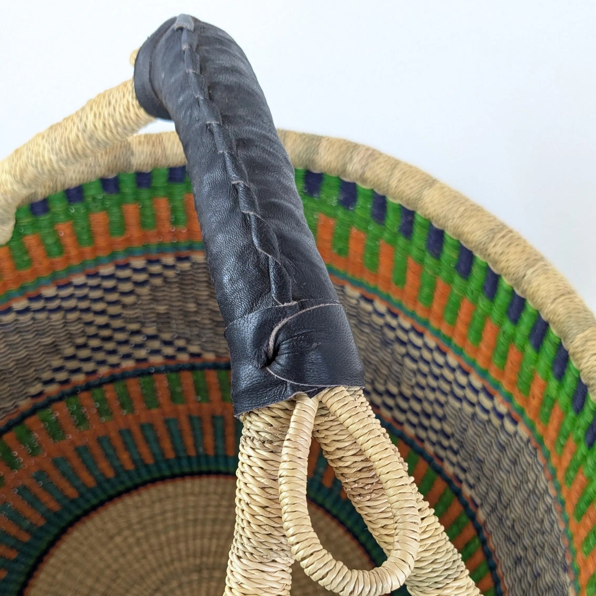 Woven basket with a black leather handles on a white background