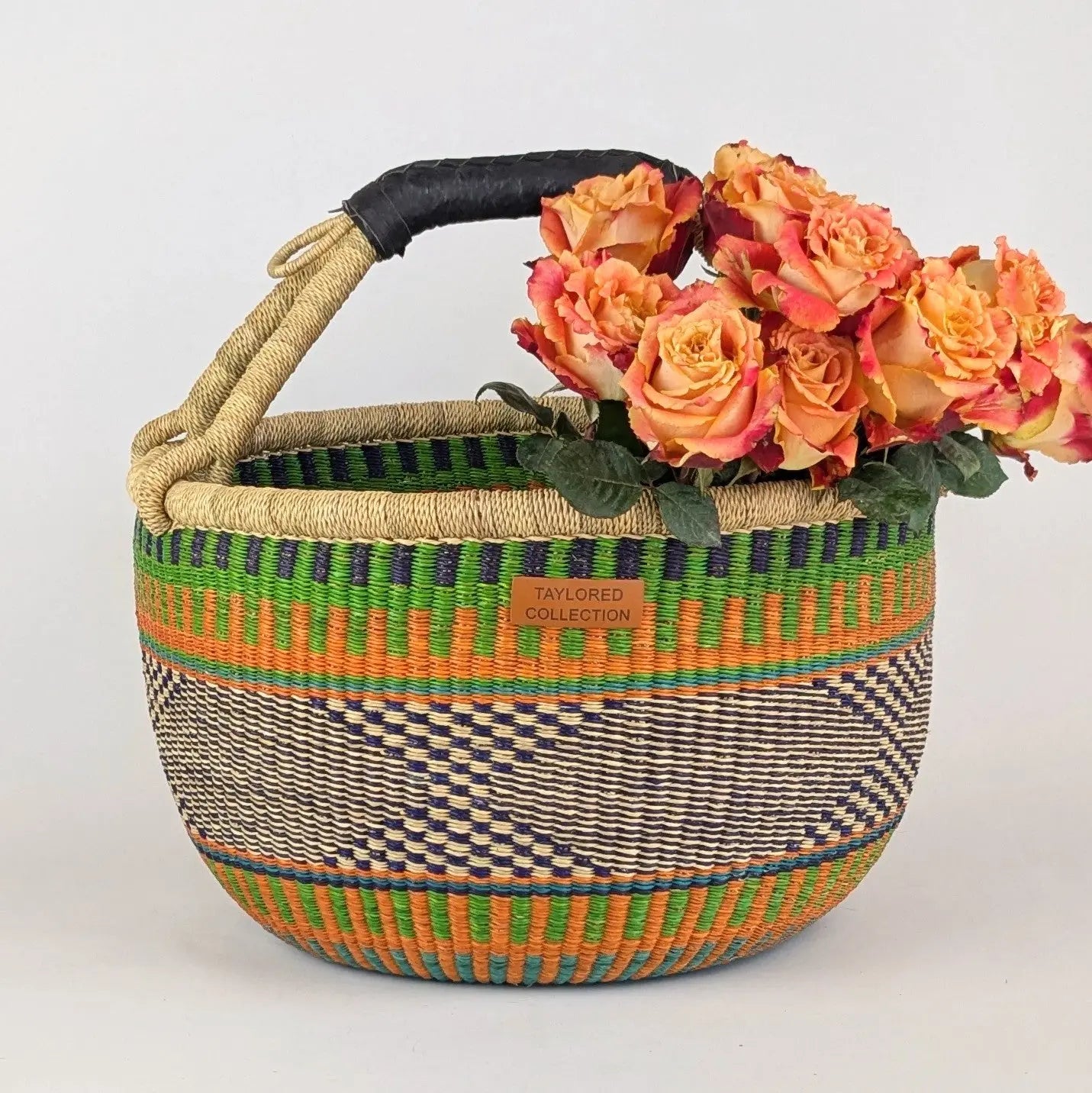 Colorful woven basket with a handle, filled with flowers on a white background