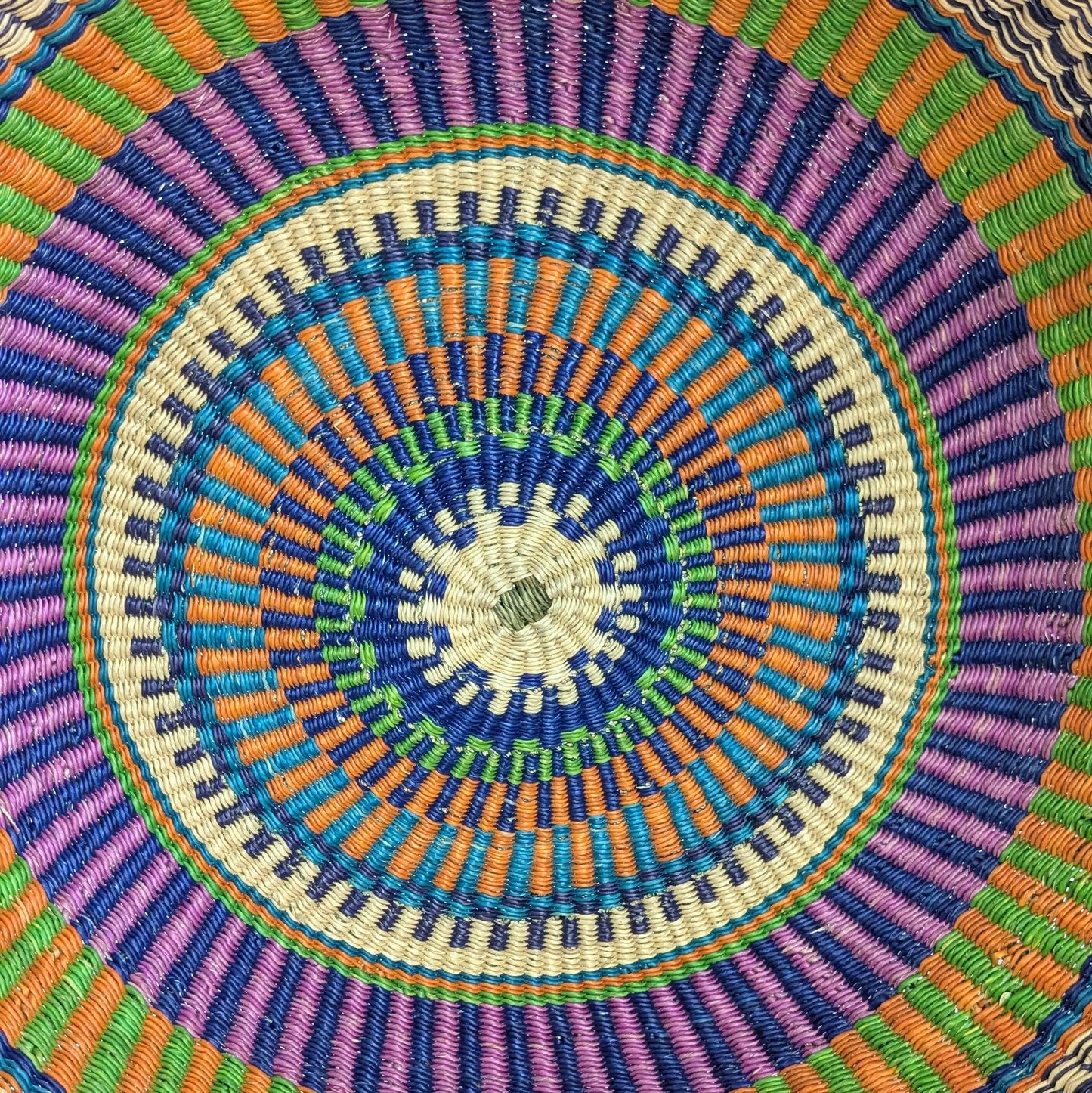 Close-up of a colorful woven circular pattern with concentric circles.