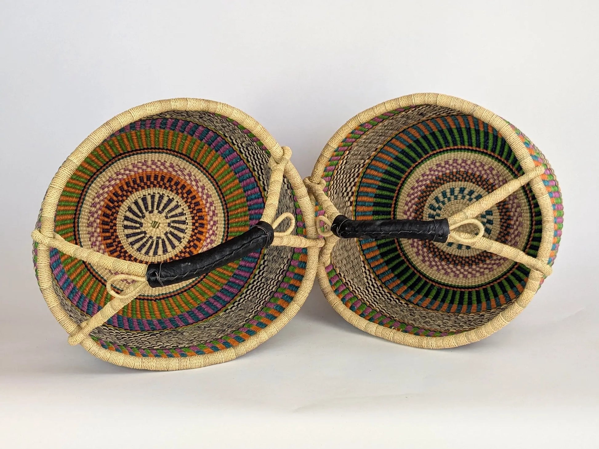 Two woven baskets with colorful patterns on a white background