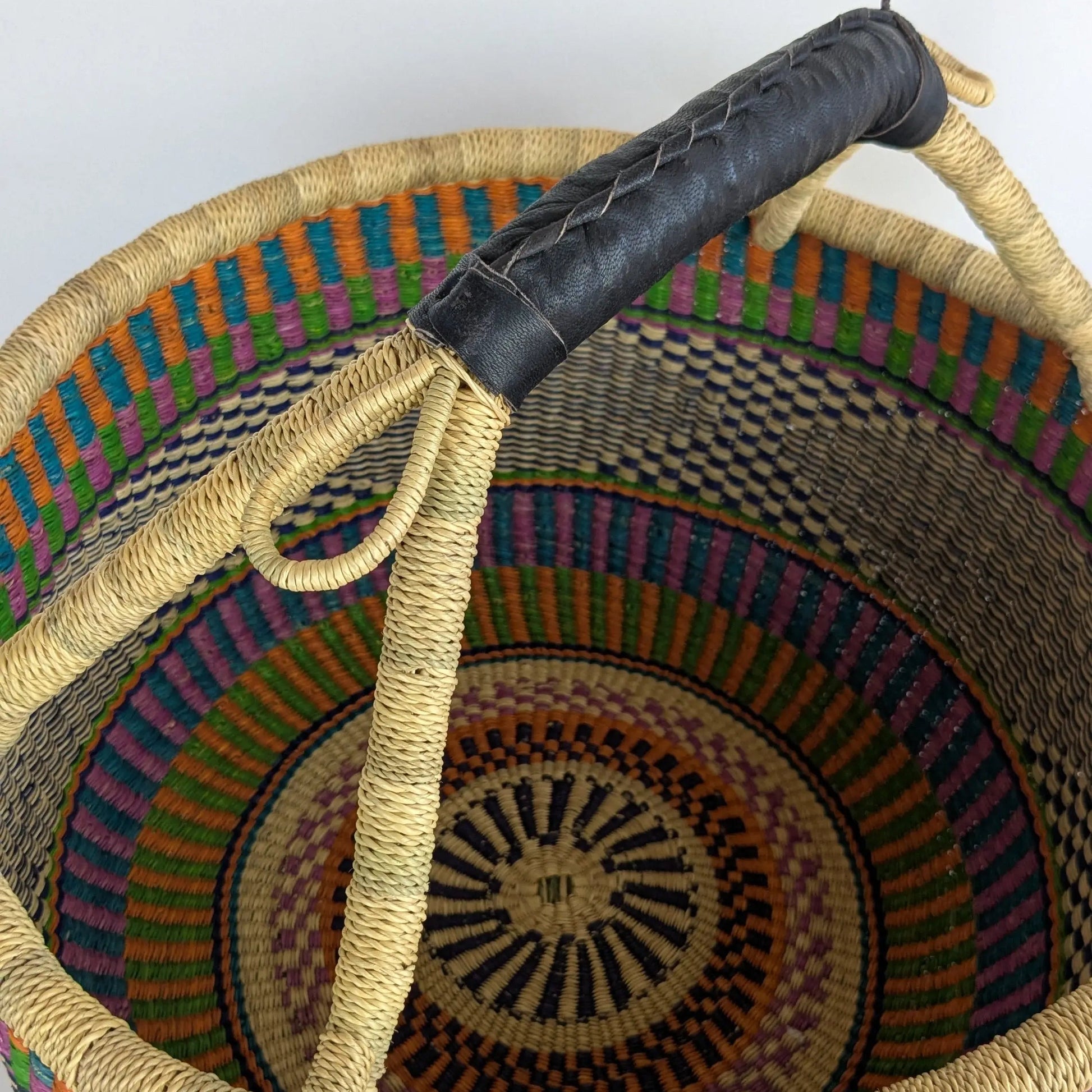 Woven basket with a black handle on a white background