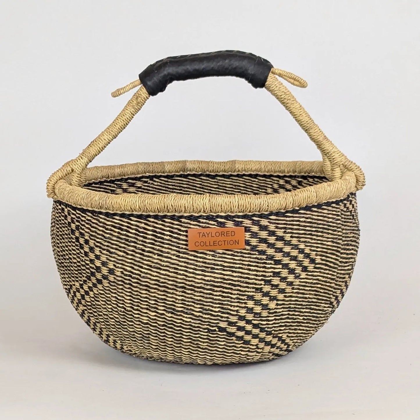 Woven basket with a black handle on a white background