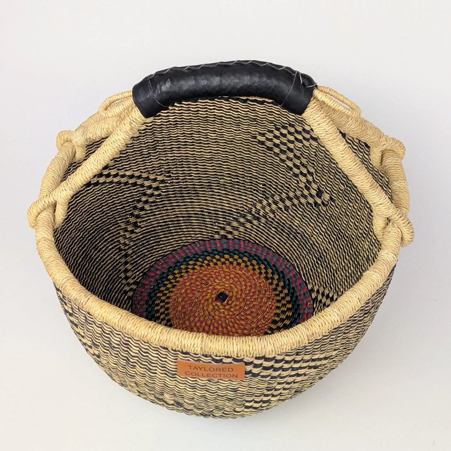 Woven basket with a black handle on a white background