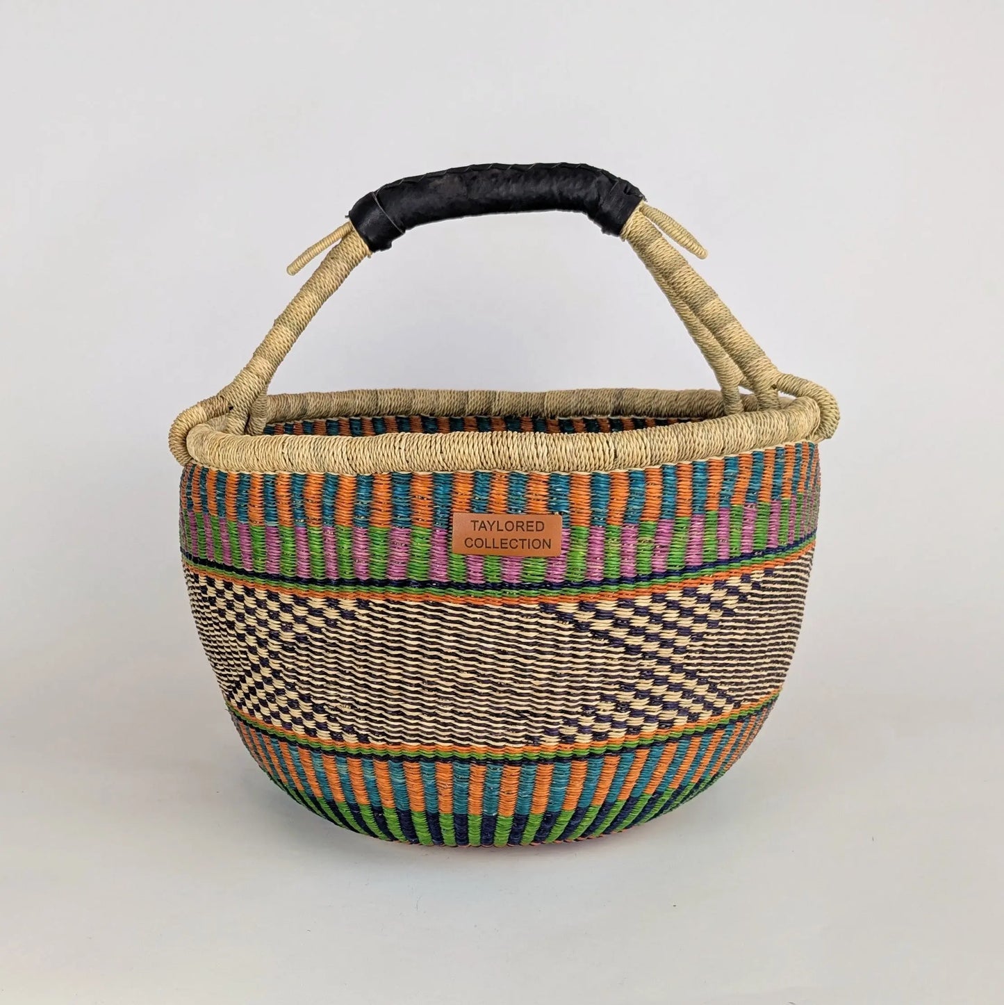 Woven basket with colorful patterns and a black handle on a light gray background