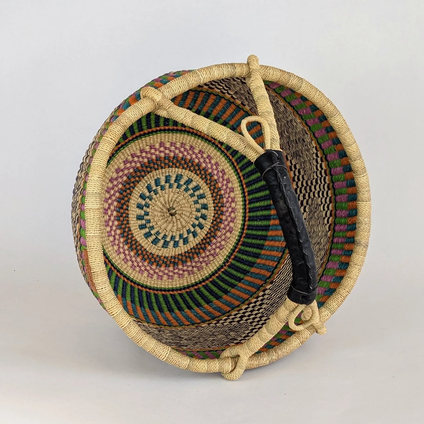 Woven basket with colorful patterns on a light gray background