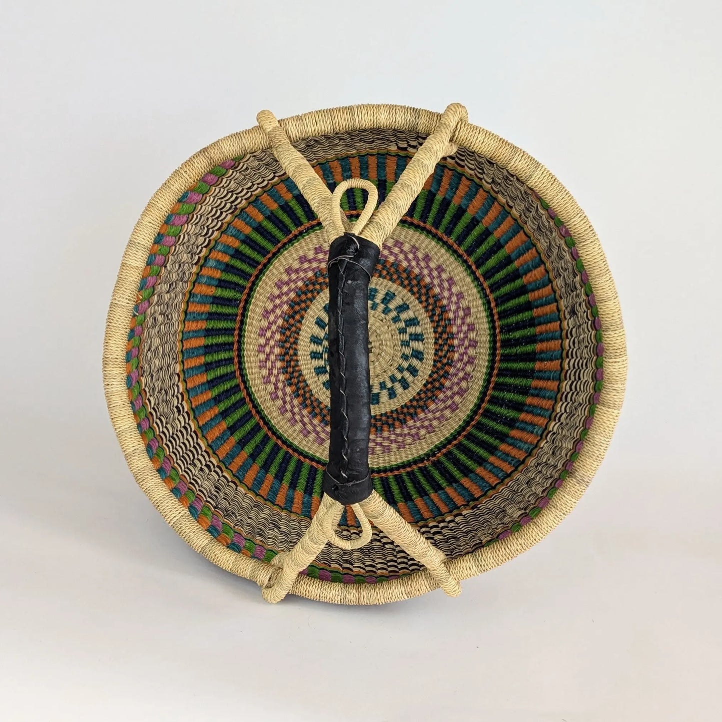 Woven basket with a black handle on a light gray background