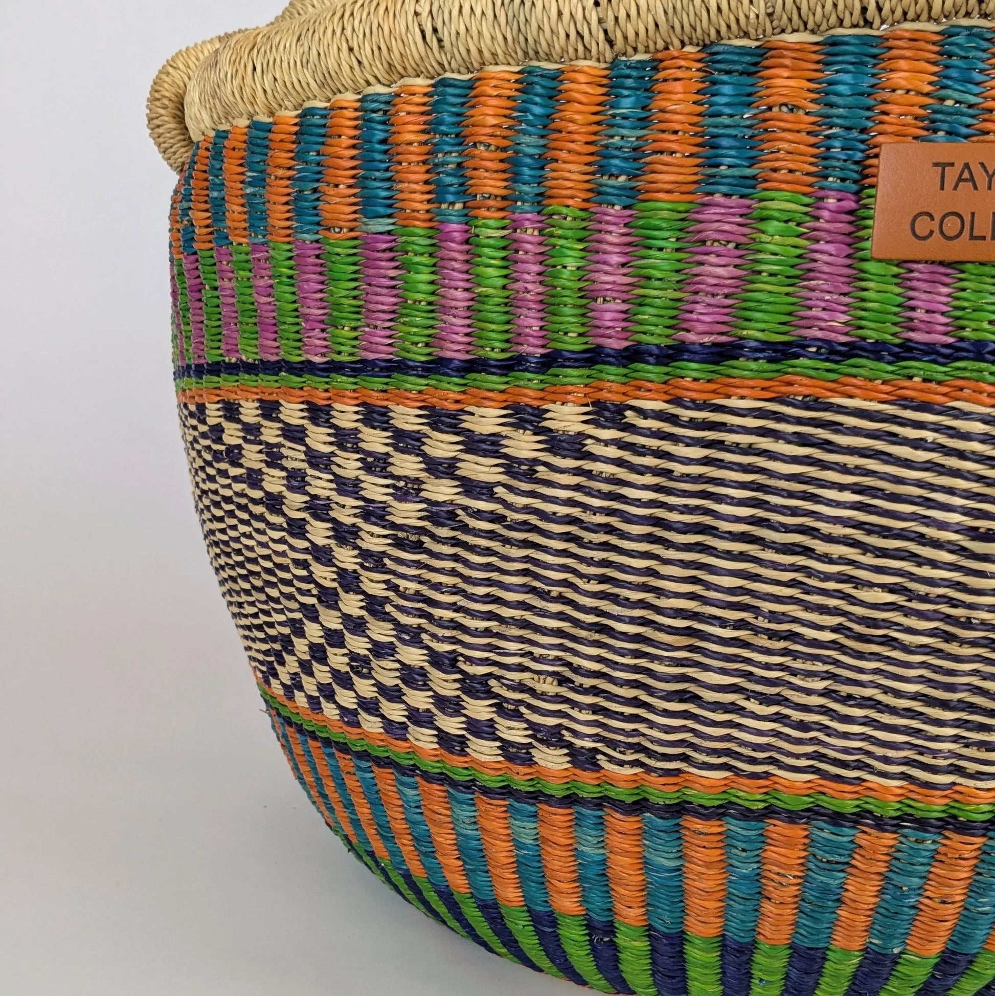 Colorful woven basket with a visible brand label on a light gray background