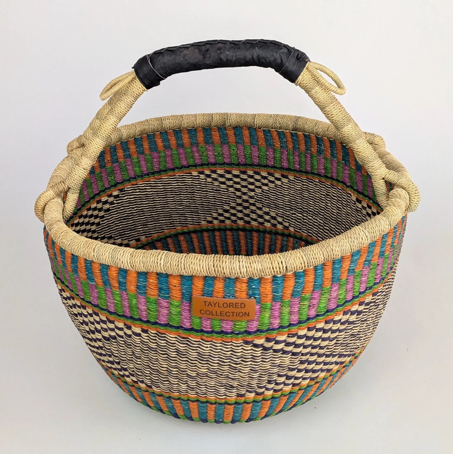 Woven basket with colorful rim and black handle on a white background